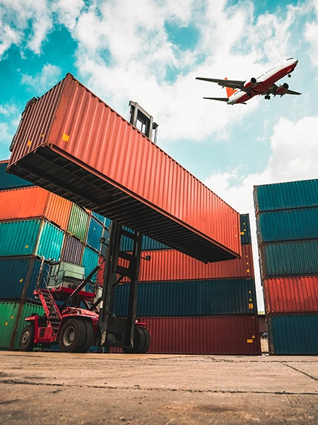 A plane flies over freight containers